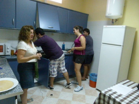 Lourdes Palacios, monitora del curso, junto con tres jóvenes durante la realización de las primeras comidas