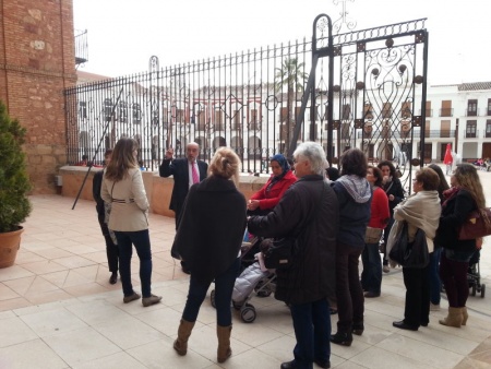 El alcalde y el grupo de Cruz Roja ante la "Biblia en piedra" del pórtico de la Iglesia de la Asunción