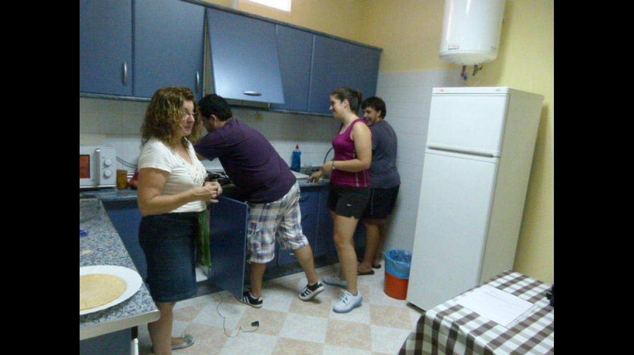 Lourdes Palacios, monitora del curso, junto con tres jóvenes durante la realización de las primeras comidas