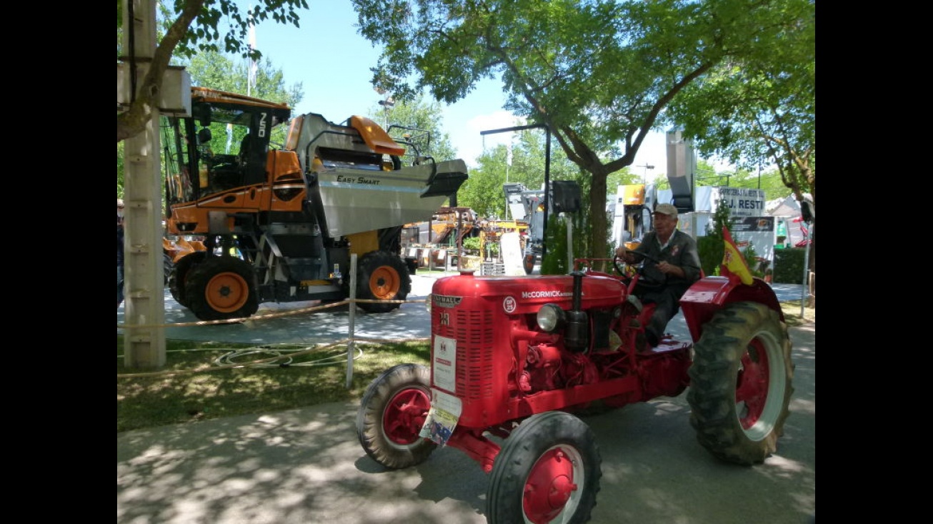 Un tractor de 1950 pasa entre moderna maquinaria