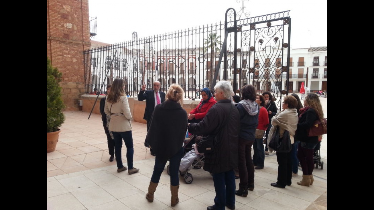 El alcalde y el grupo de Cruz Roja ante la "Biblia en piedra" del pórtico de la Iglesia de la Asunción