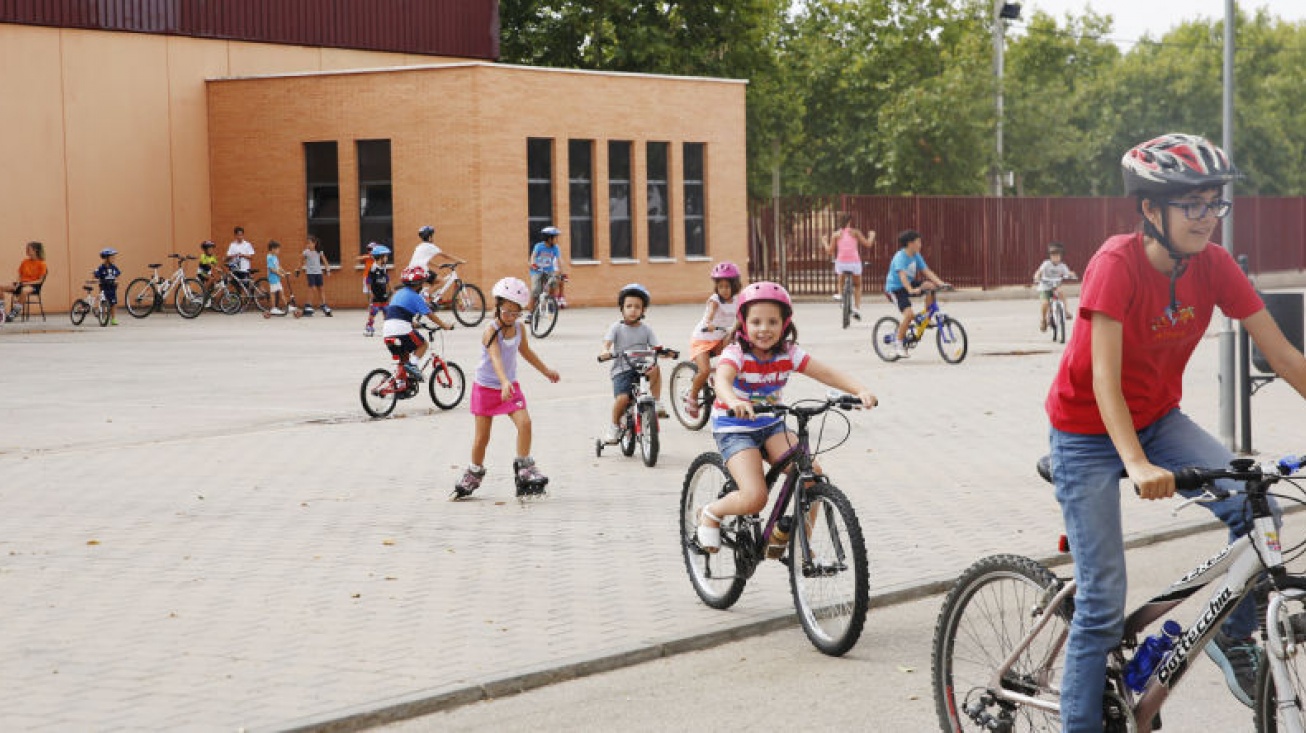 Los niños del campamento urbano recorren en bicicleta el recinto ferial